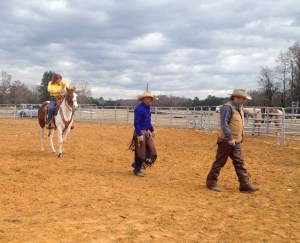 mounted shooting hands chuckle helping a guest try her hand at the sport